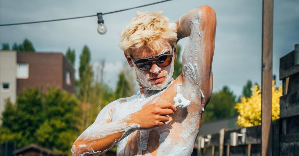 young blonde man shaving his whole body