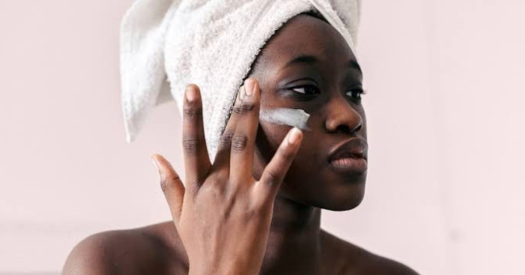 young black woman using skincare cream on her face
