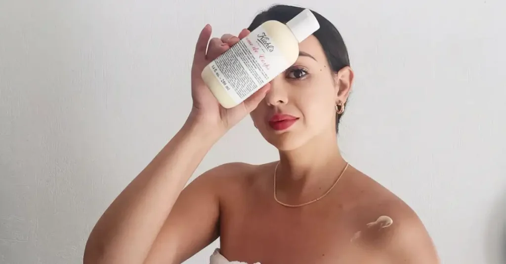 woman holding a kiehl's skincare product in front of her face