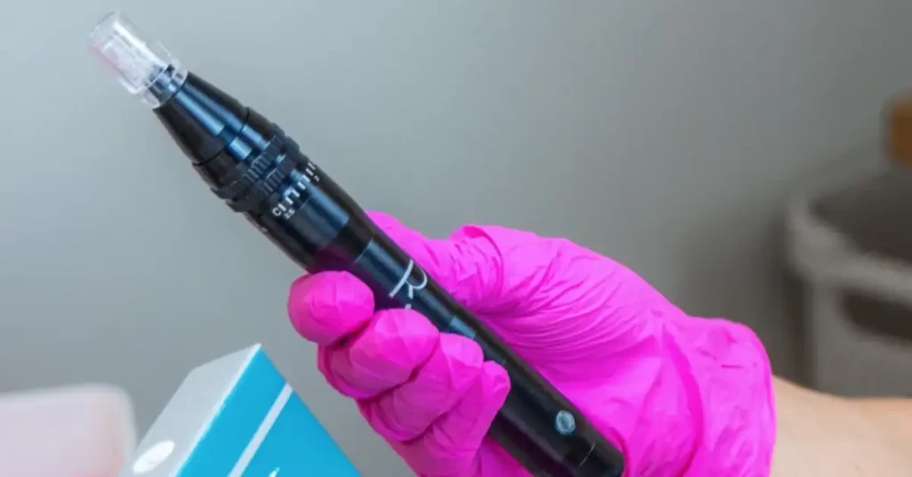 woman in pink gloves holding black microneedling pen