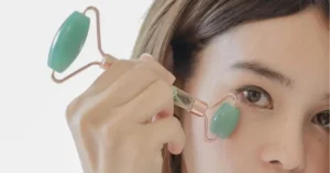 young woman using jade roller on her cheek