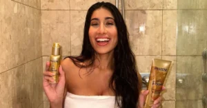 brunette woman in holding pantene hair products in the shower
